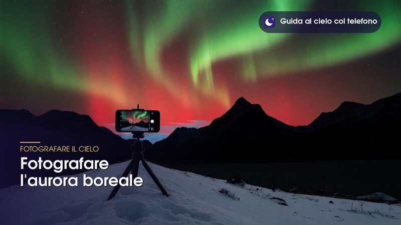 Telefono su treppiede sulla neve davanti a un'aurora rossa e verde, per fotografare l'aurora boreale